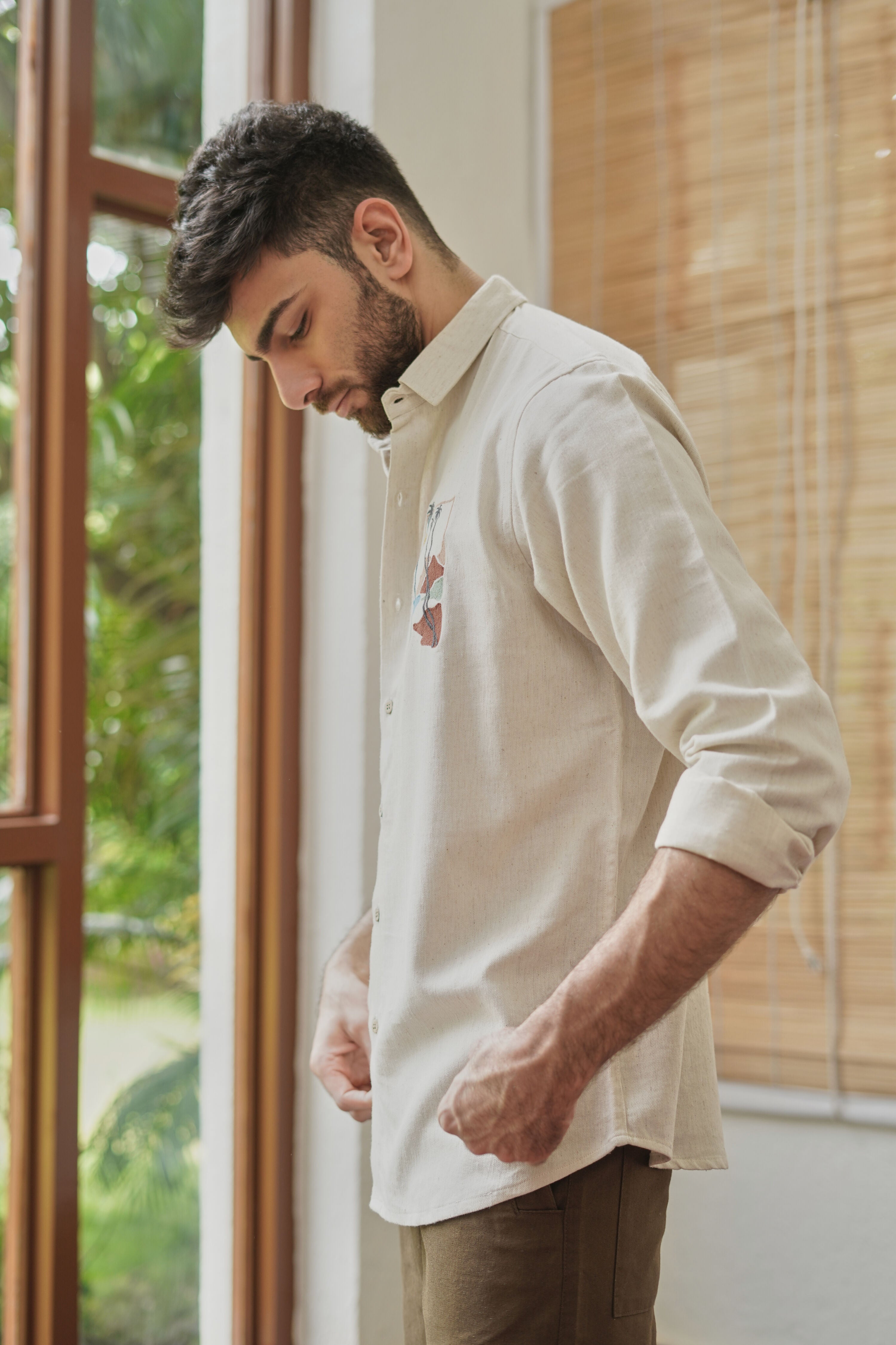 Close-up of embroidered chest motif on beige cotton shirt