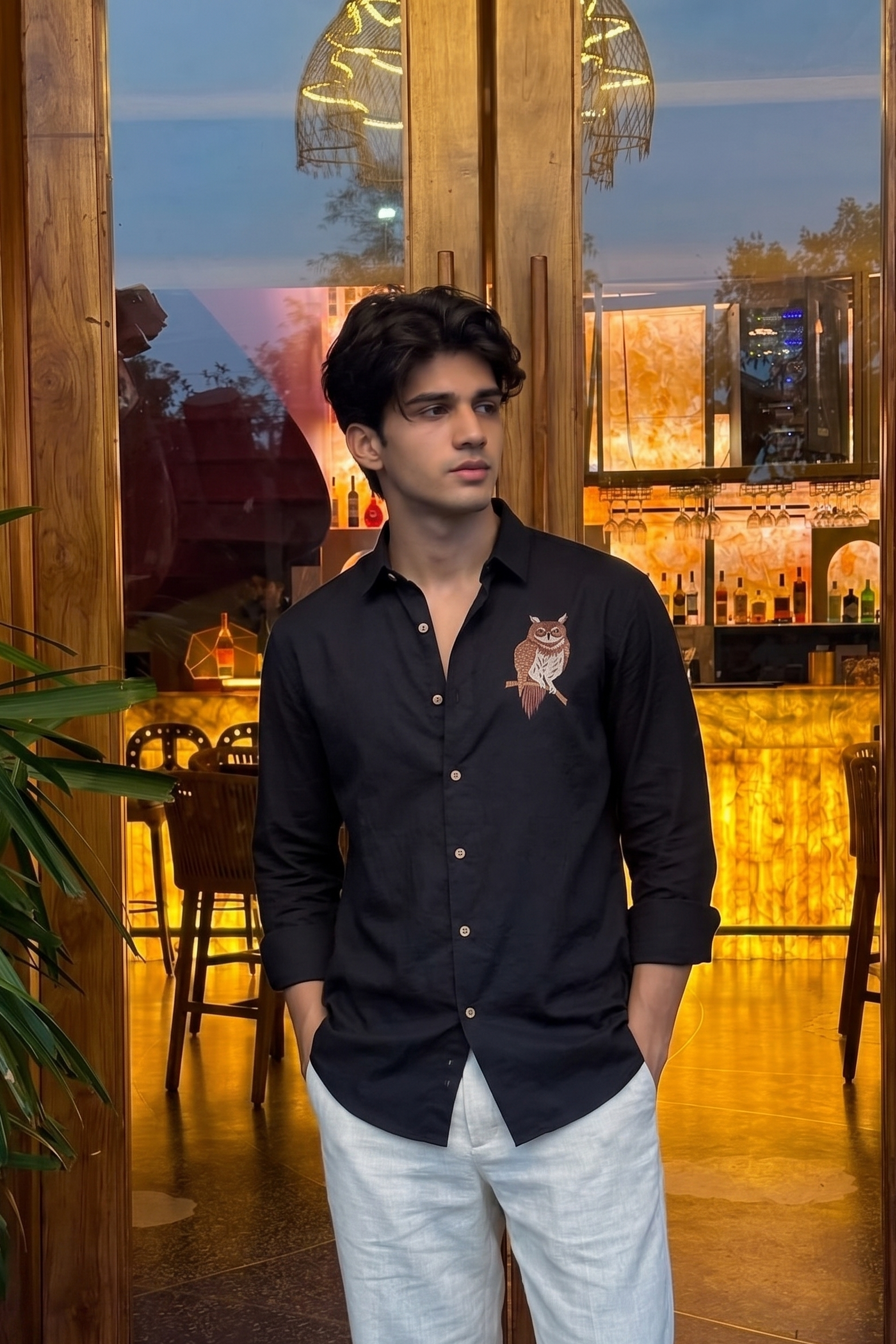 Man wearing a black shirt with an owl design in a restaurant setting