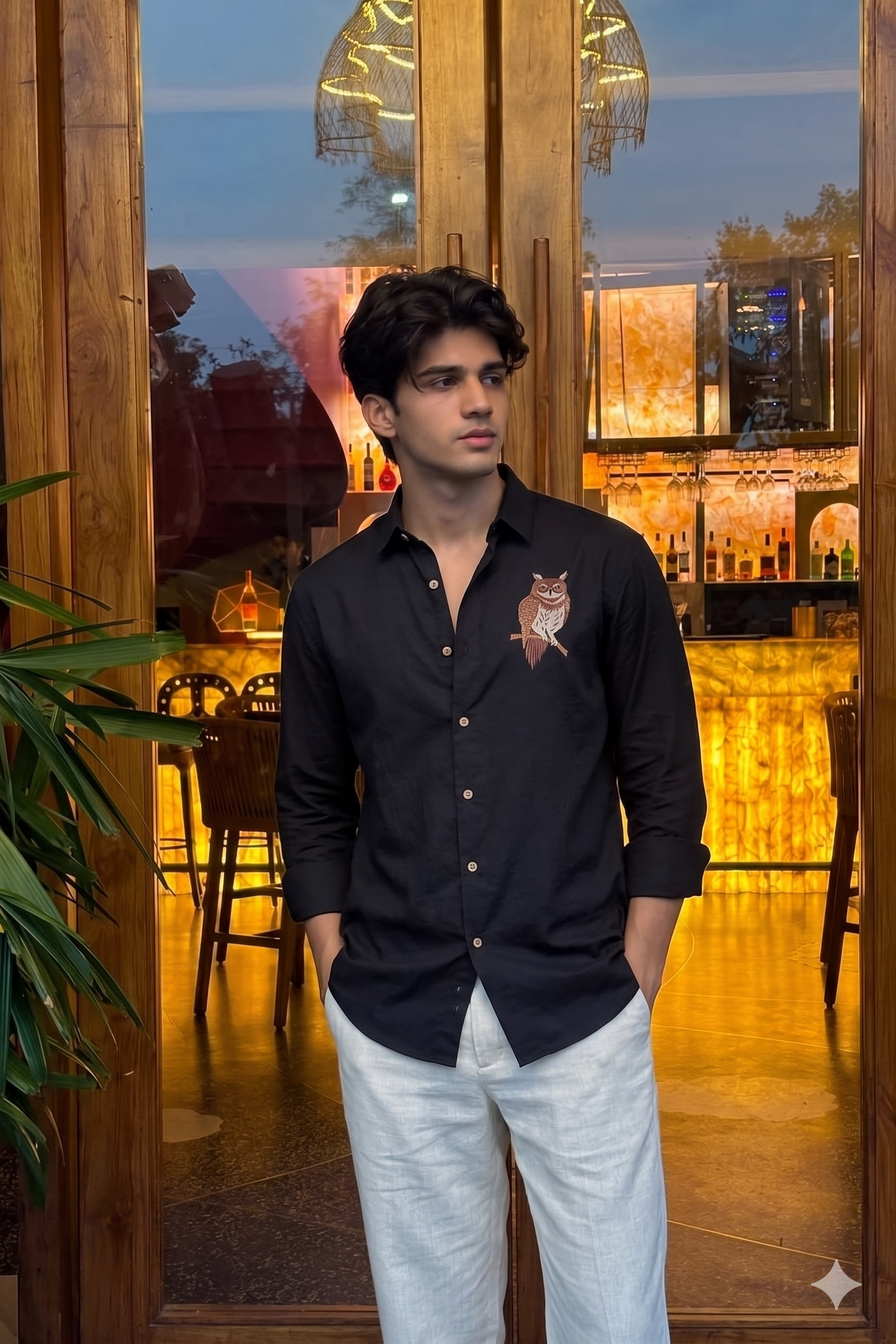 Man wearing a black shirt with an owl design in a restaurant setting